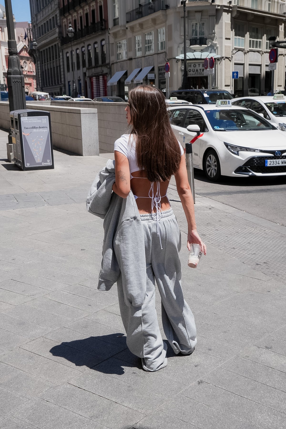 Vista trasera de modelo caminando por la calle luciendo el pantalón gris oversize de Waenn y top con lazadas, estilo urbano y editorial.