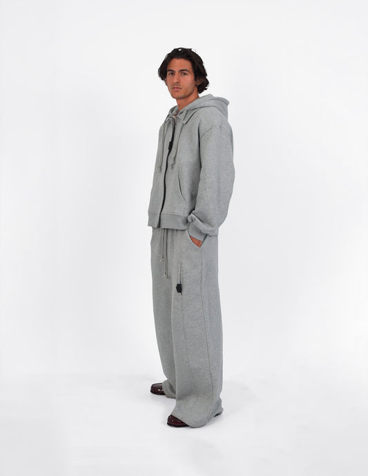Pantalón gris de corte amplio, con cuatro bolsillos, visto de cuerpo entero.
