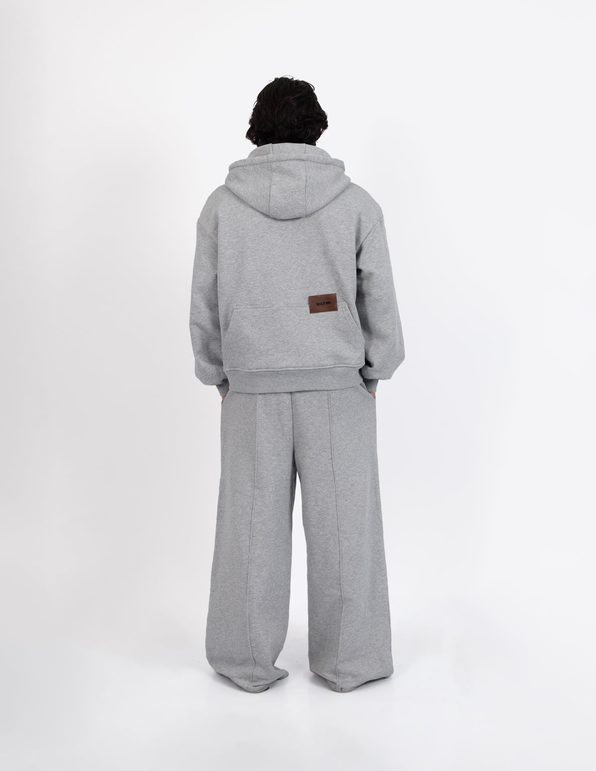 Vista trasera del pantalón de chándal gris de diseño urbano y contemporáneo, destacando la silueta holgada de la prenda.