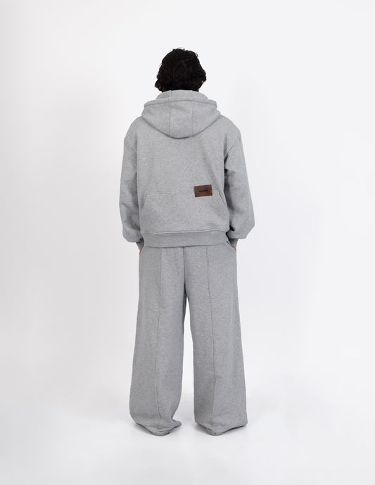 Vista trasera del pantalón de chándal gris de diseño urbano y contemporáneo, destacando la silueta holgada de la prenda.