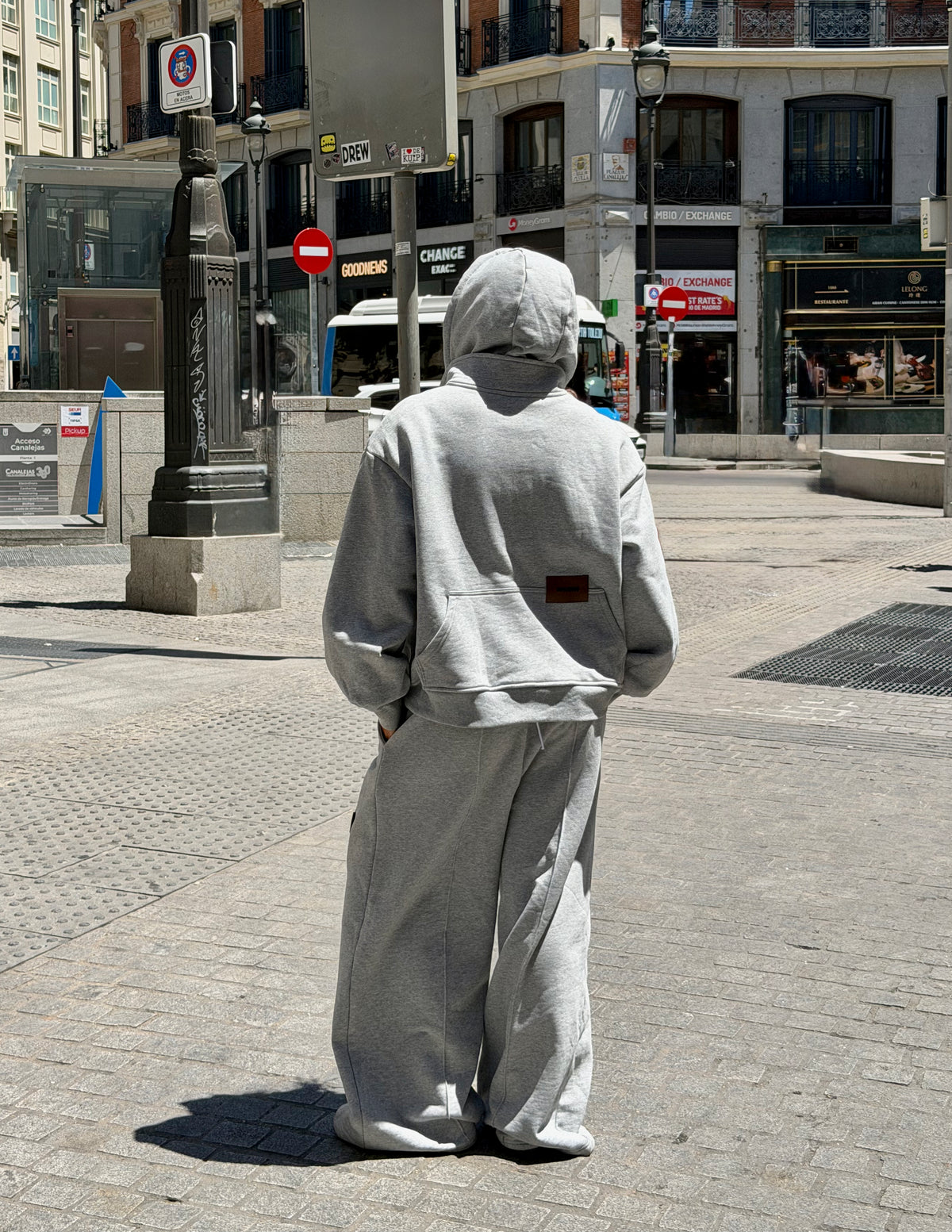 Sudadera oversize unisex gris de WAENN con detalle del logo en la espalda, presentada en un estilismo urbano en la calle.