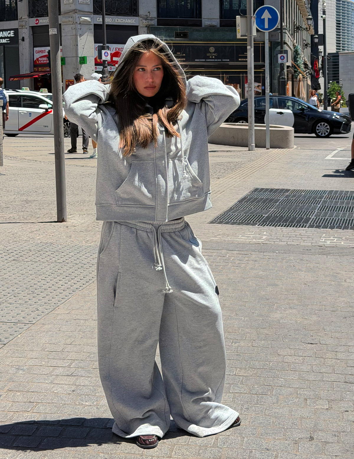 Sudadera oversize gris de WAENN con capucha y cremallera frontal, combinada con pantalón a juego en un estilismo urbano en la calle.